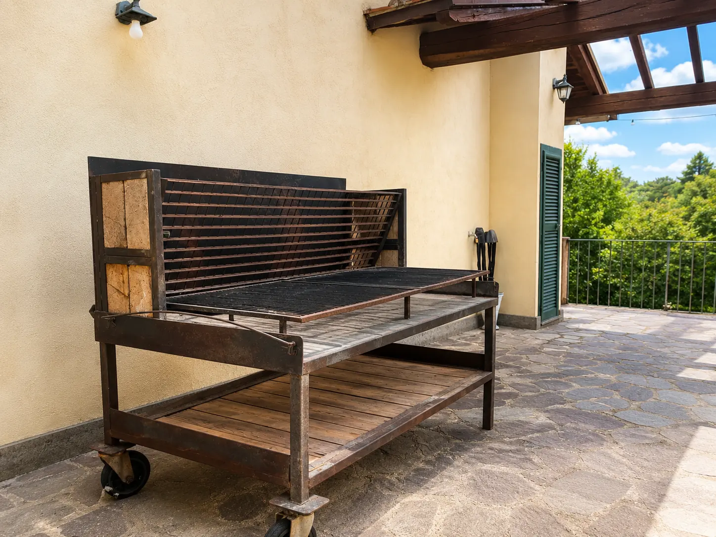 Il barbecue dell'Oasi del Verde, in ferro e legno su ruote, sotto il porticato accanto alla casa