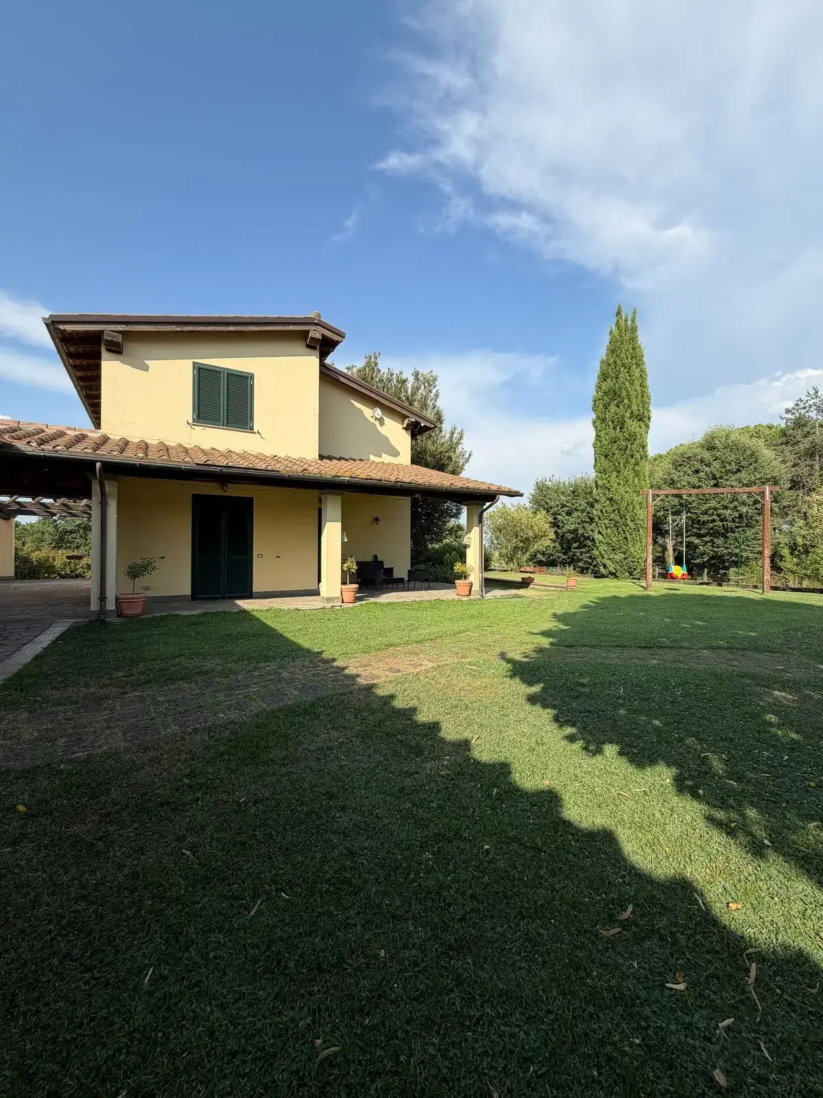 La casa dell'Oasi del Verde con un cipresso e il cielo estivo della Tuscia