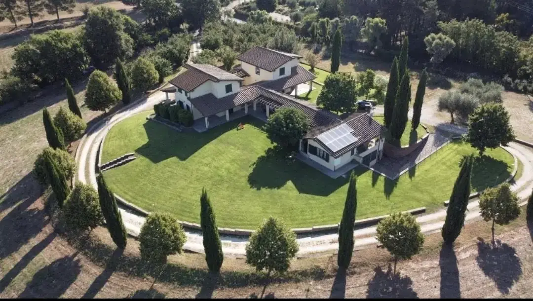 Veduta aerea dell'Oasi del Verde: la casa al centro del grande prato circondato da cipressi e uliveti