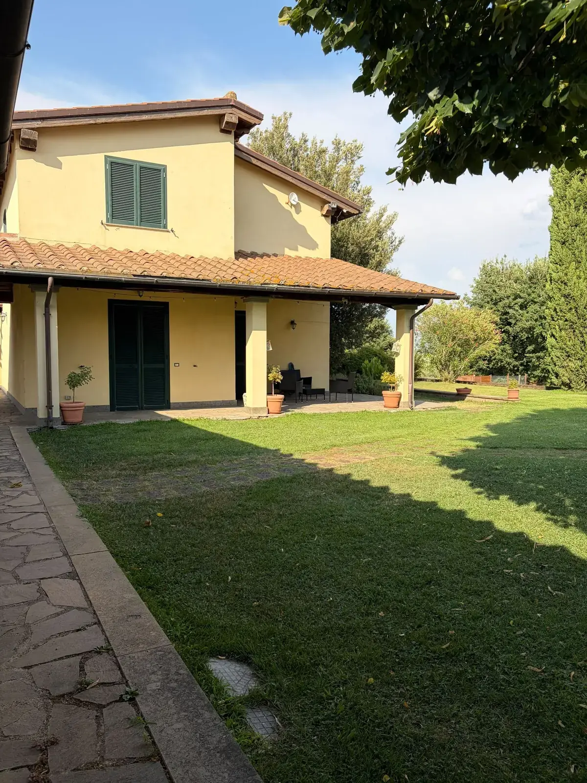 Il vialetto in pietra lungo il prato che conduce al porticato della casa